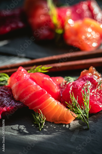 Portions of salted salmon with herbs on dark background