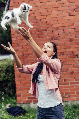 Young Smiling Girl Throws and Catches her White Cat.