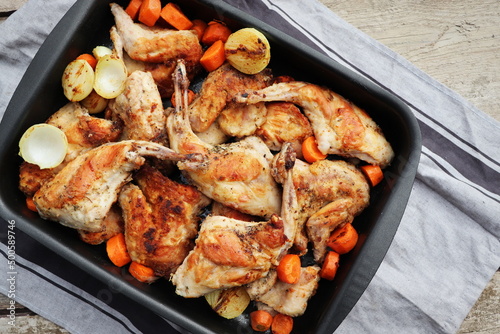 Roasted Rabbit Haunches in Pan with Stewed Vegetables on Rustic Wooden Table Surface
