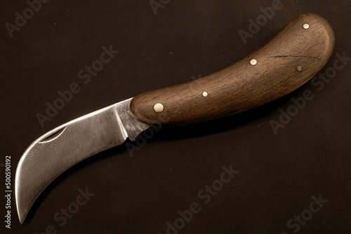 folding pruning knife with curved long blade on vintage paper background