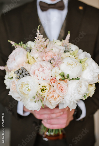 Groom holding beautiful white wedding bouquet. Closeup