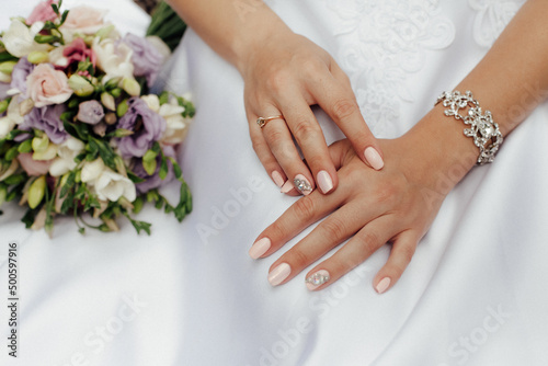 Bride in a stylish white wedding dress. Nearby lies a stylish bouquet of colorful flowers.