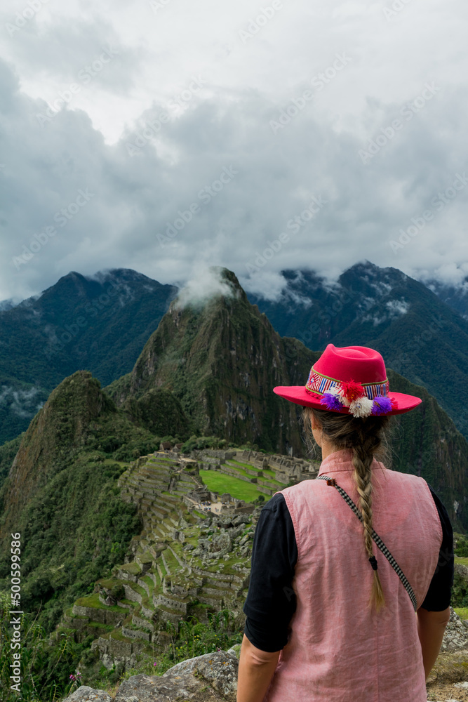 Photograph of Machu Picchu. Woman with Inca hat in the mountains