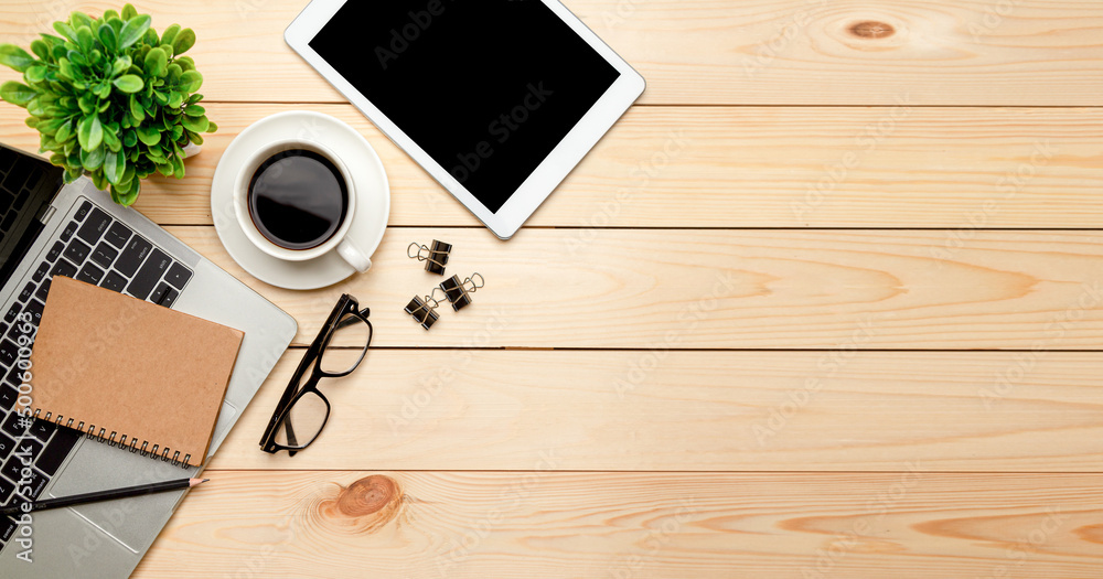 Top view office table desk. Workspace with blank, office supplies,Laptop, pencil, green leaf, and coffee cup on wood background. Top view office table desk. Workspace with blank, office supplies,Laptop, pencil, green leaf, and coffee cup on wood background.
