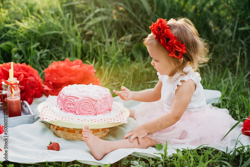 second birthday of little girl. Two years old girl sitting near celebration decorations and eating her birthday cake. Cake Smash photo