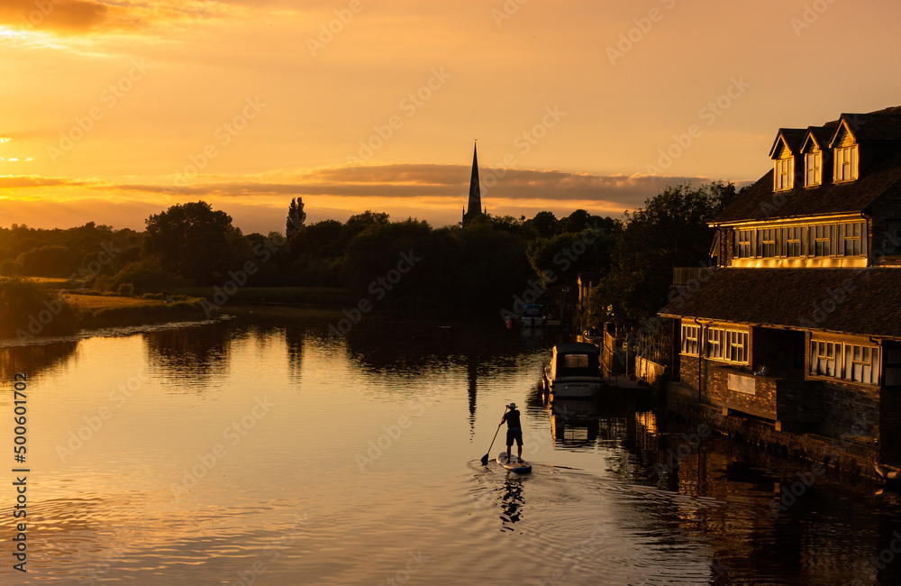 St Ives, Cambridgeshire, England, UK - View from St Ives Bridge at sunset with man on paddle boat on River Ouse