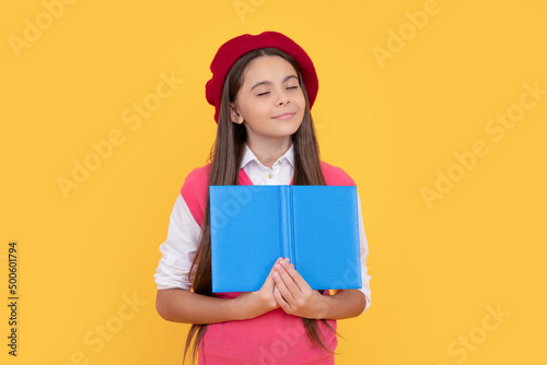 dreamy teen school girl in french beret reading book on yellow background, imagination