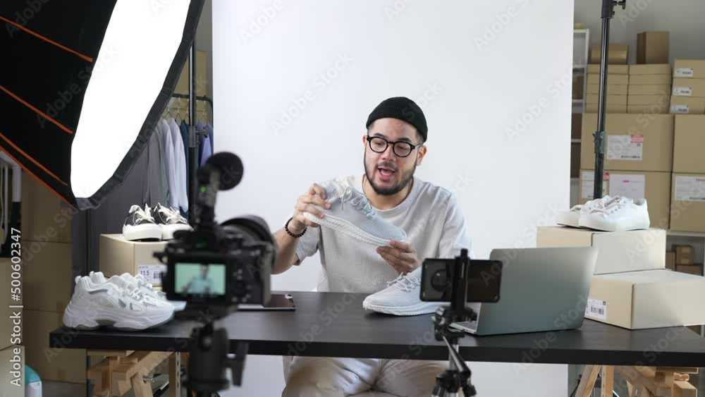 Young attractive Asian man blogger or vlogger looking at camera reviewing product and merchandise. Business online influencer on social media concept.