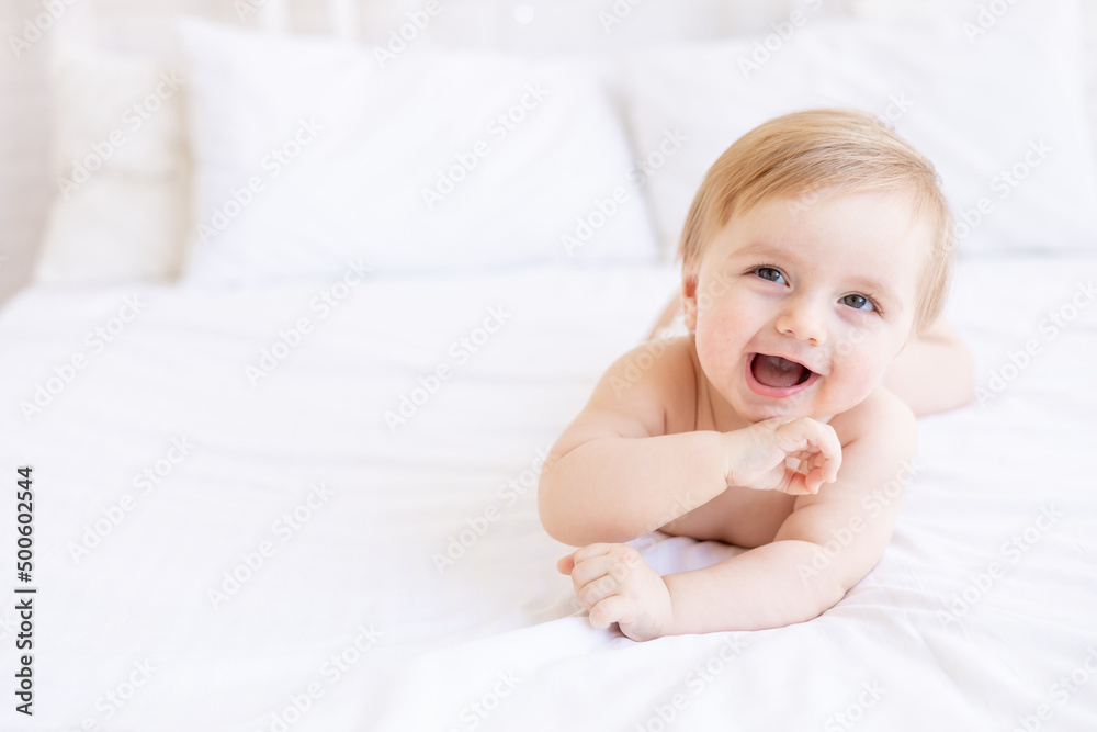 laughing or smiling baby boy blond with big eyes close-up or portrait in a crib at home, the concept of children's goods and accessories laughing or smiling baby boy blond with big eyes close-up or portrait in a crib at home, the concept of children's goods and accessories