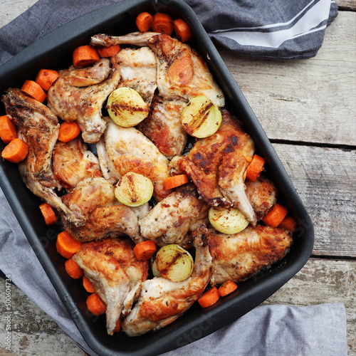 Roasted Hare Haunches in Pan with Stewed Vegetables on Rustic Wooden Table Surface