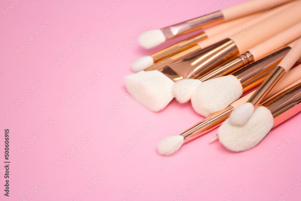 Cosmetic white brushes, everyday makeup tools on pink background, closeup. Flatlay.