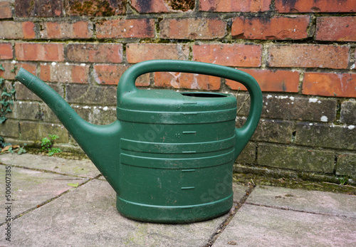 green watering can on patio surface. Plastic watering can for gardening use. 