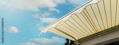 Photography retractable awning installed on wall over house window against blue sky
