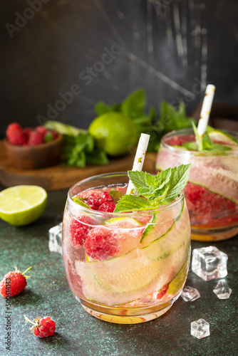 Soft drinks, healthy beverage, slimming water. Refreshing detox drinks made from organic raspberries, cucumbers, lime and mint leaves on a stone table. Copy space.