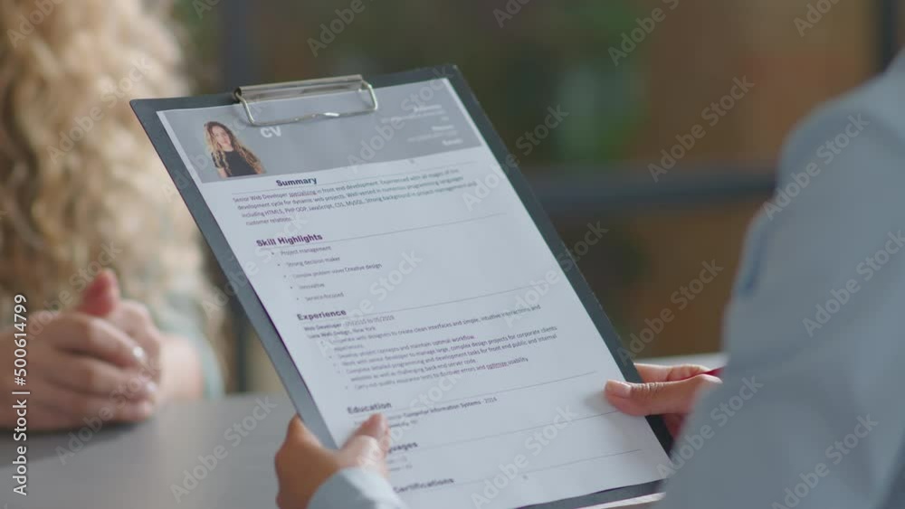 Over the shoulder shot of Caucasian businesswoman giving CV on clipboard to HR manager and answering questions during job interview in office