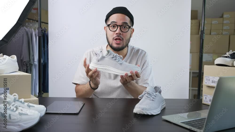Young attractive Asian man blogger or vlogger looking at camera reviewing product and merchandise. Business online influencer on social media concept.