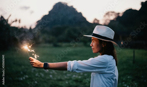 Asian woman playing fireworks sparklers in the evening.