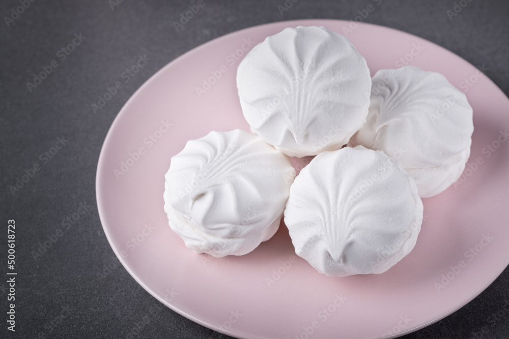 White marshmallows on a pink plate on a grey table