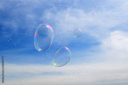 dreams, inspiration, fantasies concept - light airy transparent soap bubbles fly in the blue cloudy sky. © Mariia