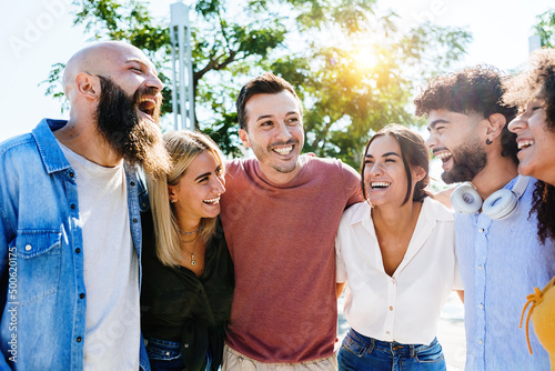 Group of smiling young friends having fun together outdoors - Multiracial millennial people laughing while hanging out in city street on summer vacation - Friendship and unity concept