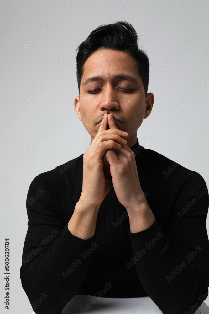 Vertical headshot of Asian man with closed eyes and negative face expression. Vertical headshot of Asian man with closed eyes and negative face expression.