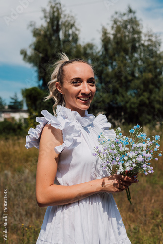 A young beautiful girl holds flowers in her hands and smiles