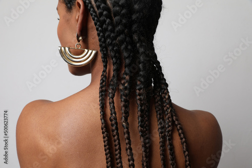 Close-up of African young woman with dark braids posing on white background.