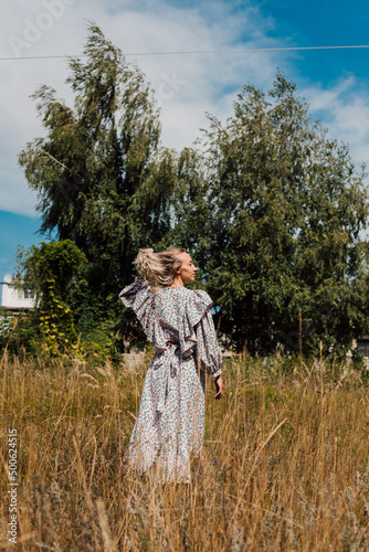 A young girl in a long dress walks in the field