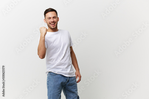 Big luck. Happy overjoyed tanned handsome man in basic t-shirt clenches his fist smile posing isolated on over white studio background. Copy space Banner Mockup. People emotions Lifestyle concept