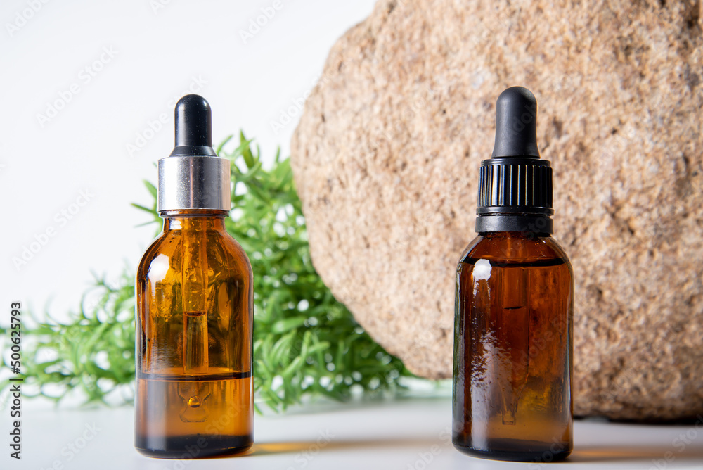 Cosmetic oil in a brown bottle with a pipette on a stone background. Cosmetic oil in a brown bottle with a pipette on a stone background.