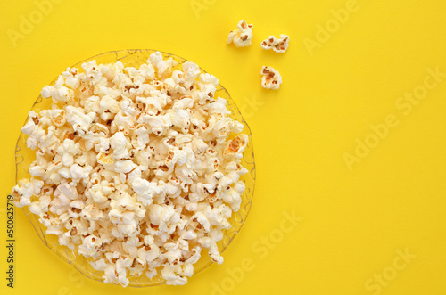 a plate of popcorn on yellow background close up, copy space