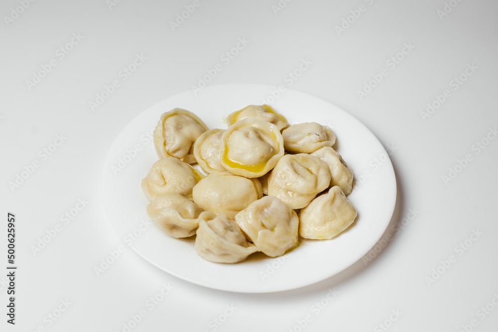 Hot delicious dumplings drizzled with butter in a plate on a white background Hot delicious dumplings drizzled with butter in a plate on a white background