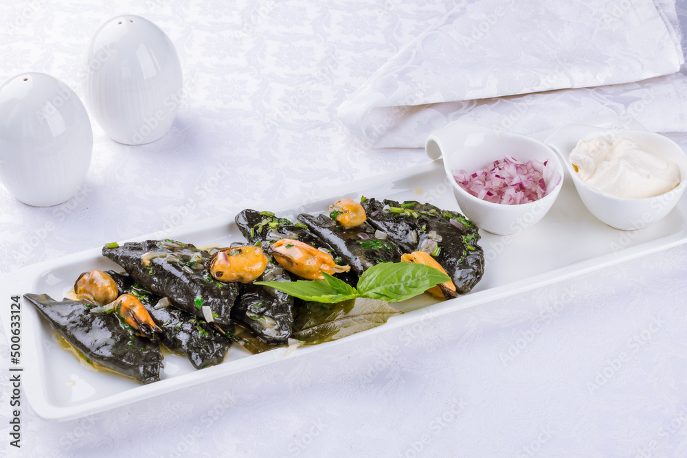 black ravioli with crab and mussels on a white plate