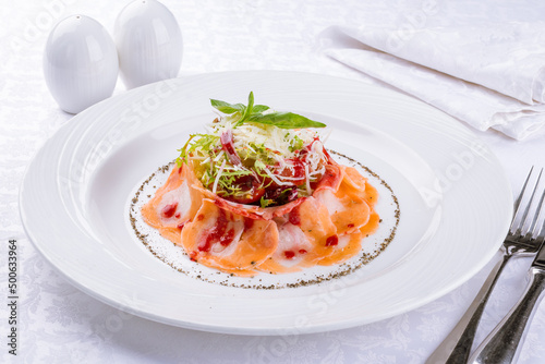 Salmon carpaccio with salad and vegetables on a white plate