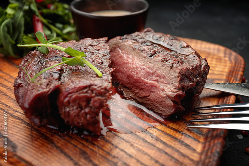 Meat steak on the wooden board, with fork and knife
