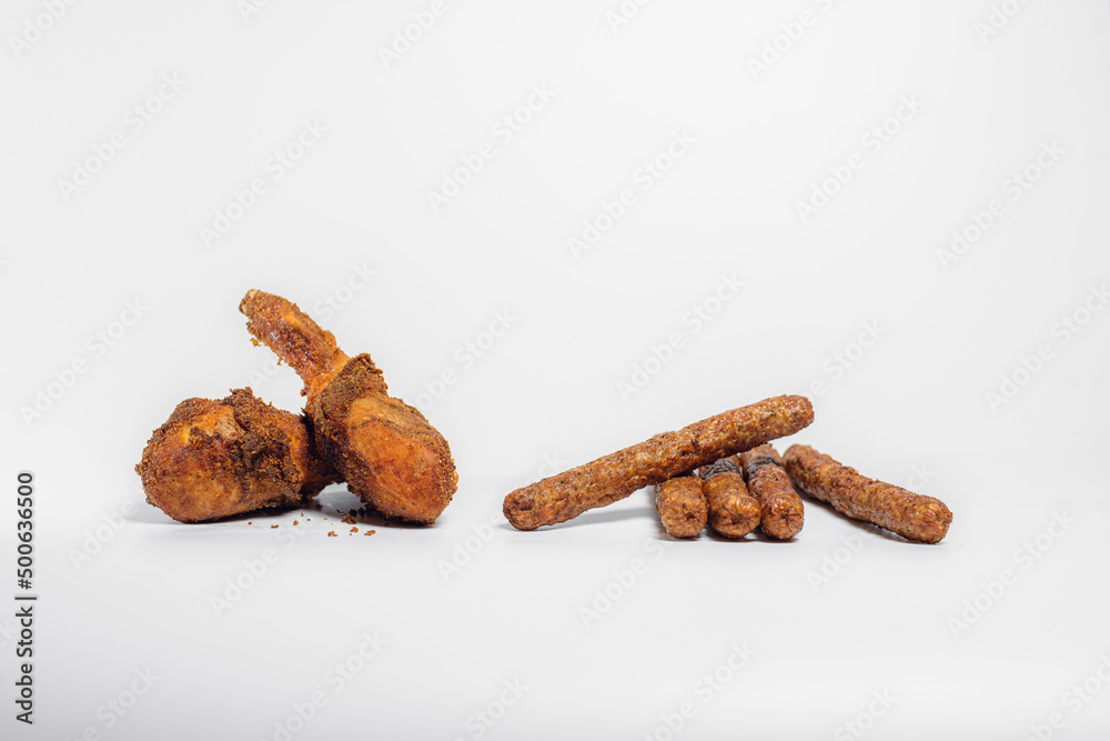 fried chicken drumsticks in oil and breadcrumbs lie on a white background in two pieces with chopsticks fried chicken drumsticks in oil and breadcrumbs lie on a white background in two pieces with chopsticks