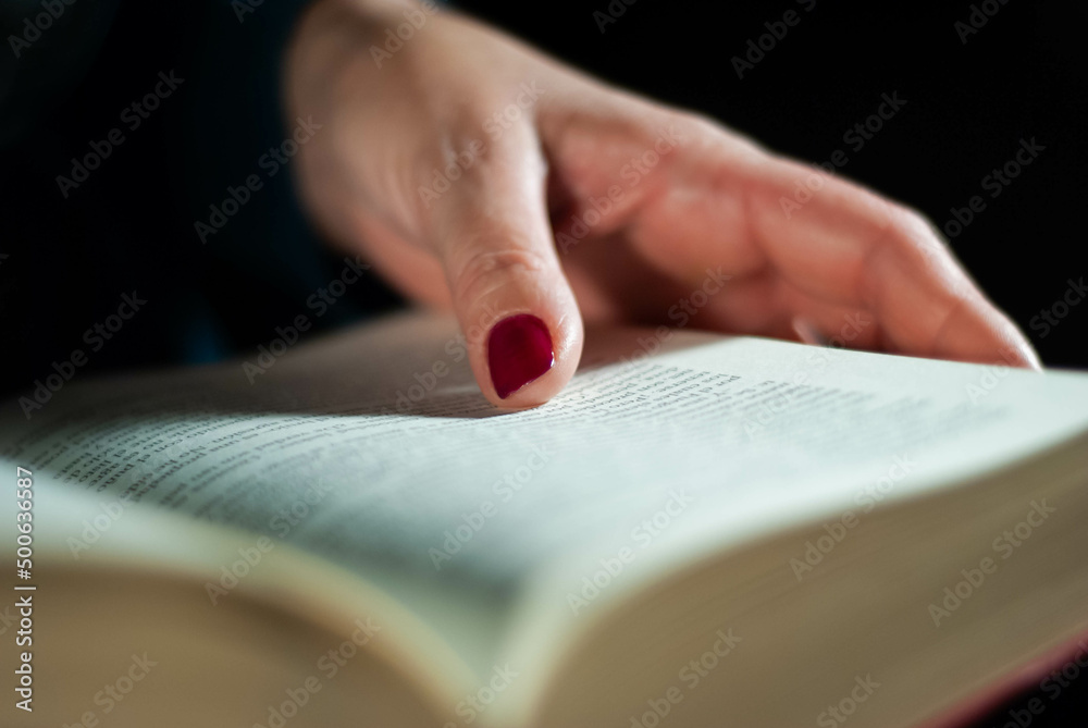 Hands holding a book that an elderly woman is reading using her fingers on the lines filled with words