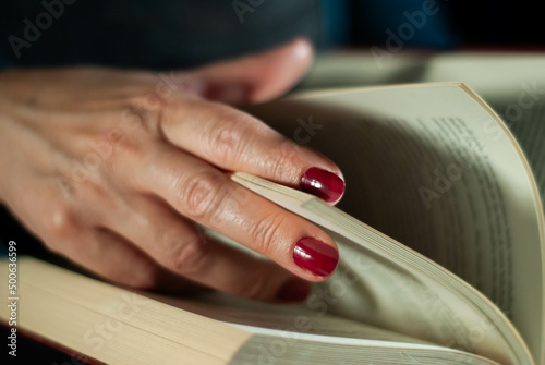 Hands holding a book that an elderly woman is reading using her fingers on the lines filled with words