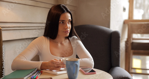 Pretty brunette woman drinking coffee in cafe