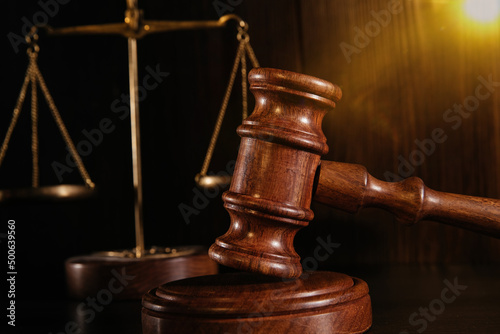 Wooden gavel and scales in a dark court room