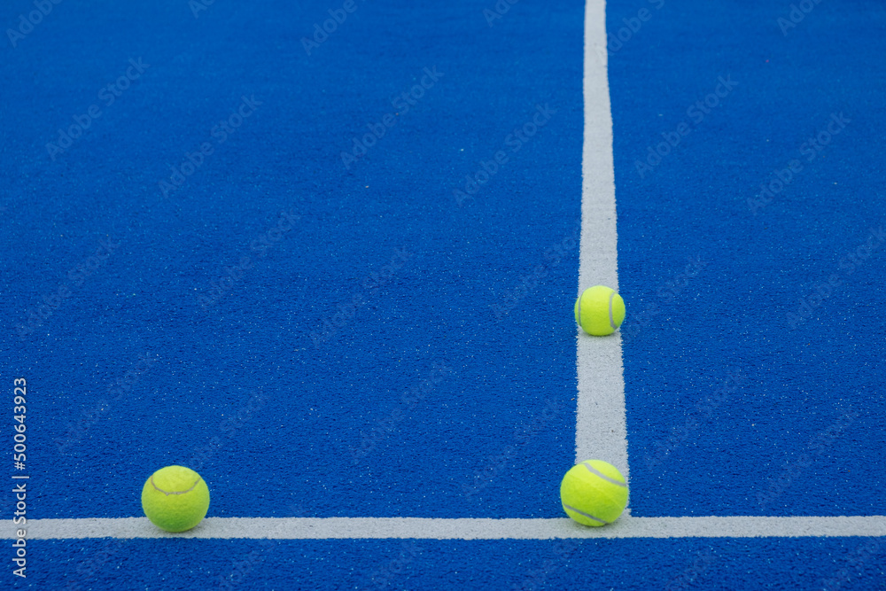 racket sports, three balls on the lines of a blue paddle tennis court