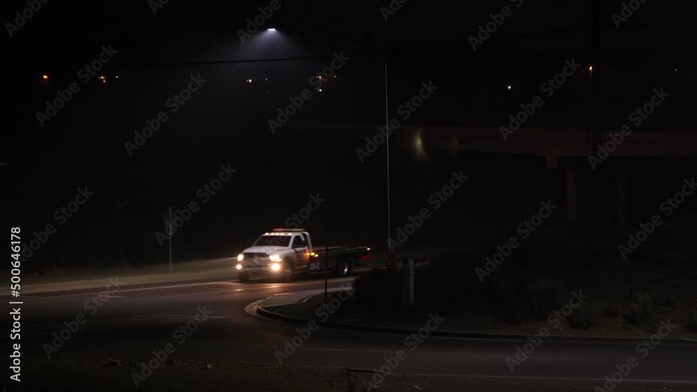 Tow truck entering freeway onramp on a dark night. Low visibility and headlight beams showing in the smoke from wildfires Tow truck entering freeway onramp on a dark night. Low visibility and headlight beams showing in the smoke from wildfires