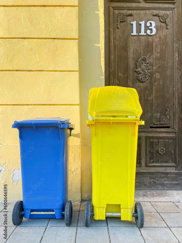 Two blue and yellow plastic containers for garbage. Separation and sorting of rubbish, vertical orientation Two blue and yellow plastic containers for garbage. Separation and sorting of rubbish, vertical orientation