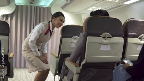 The female cabin crew was smiling and serving passengers on the flight she was willingly serving. The businessman passenger called the crew for service during the flight in travel concept.