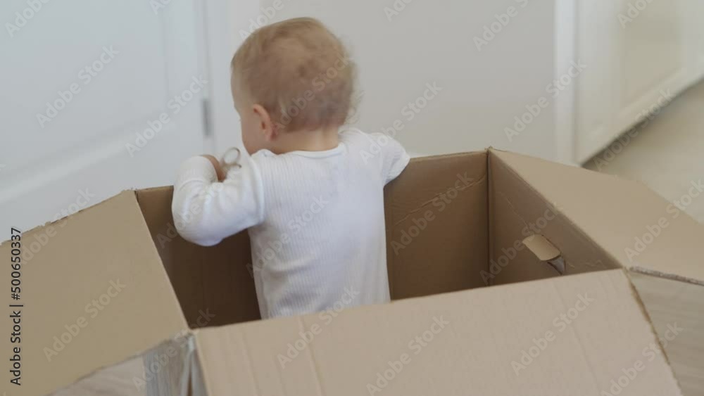 Baby playing in large cardboard package box at home. High quality 4k footage Baby playing in large cardboard package box at home. High quality 4k footage