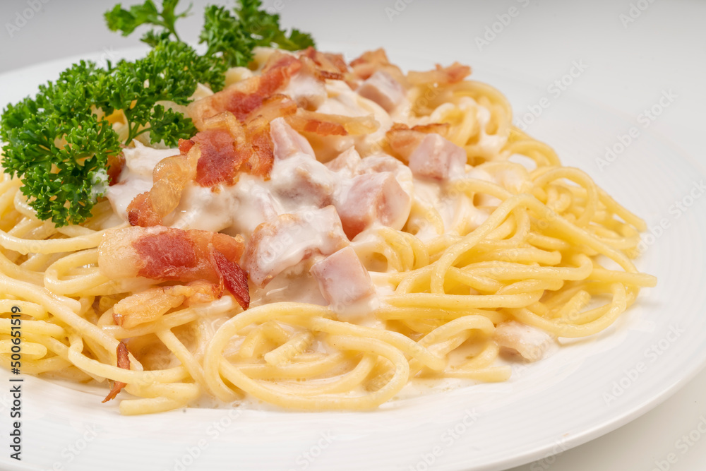 Spaghetti carbonara with Crispy Bacon and Ham on white plate on white background, Carbonara pasta with parmesan cheese and cream sauce, Traditional italian cuisine. Spaghetti carbonara with Crispy Bacon and Ham on white plate on white background, Carbonara pasta with parmesan cheese and cream sauce, Traditional italian cuisine.
