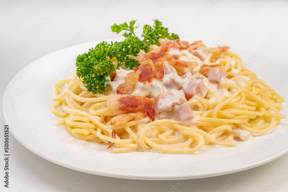 Spaghetti carbonara with Crispy Bacon and Ham on white plate on white background, Carbonara pasta with parmesan cheese and cream sauce, Traditional italian cuisine.