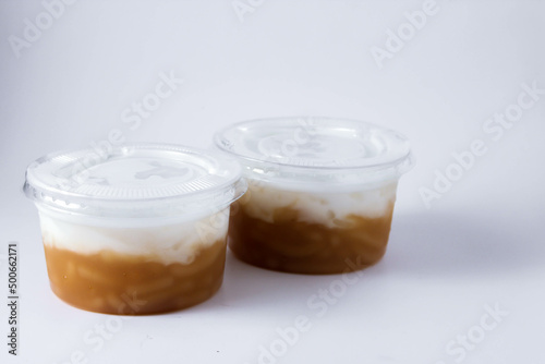 Sweet Rice Noodles with Coconut Cream in a plastic cup on a white table.
