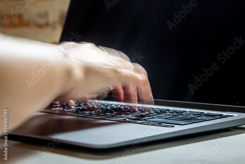 Hand typing a laptop keyboard