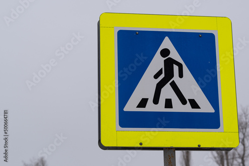 A road sign indicating a pedestrian crossing. Road sign, against the sky. An organized road crossing marked with a sign.